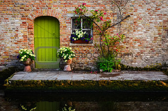 Vintage old wall with green door and flowers