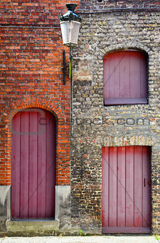 Old vintage brick wall with red wooden doors and windows