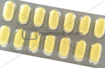 Closed up long yellow tablet in transparent blister pack
