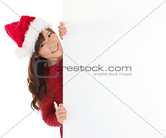 Cute Santa girl peeking from behind blank sign