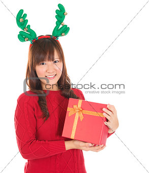 Asian Christmas woman holding gift wearing reindeer horns.