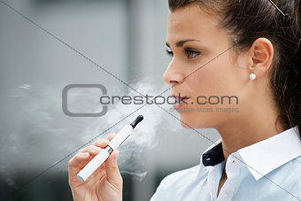 young woman smoking electronic cigarette outdoor office building