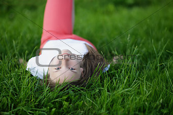 young attractive girl lying on the grass and looking to the camera