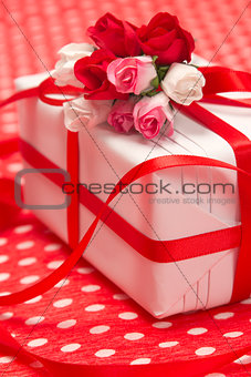White gift box with red bow and paper flowers