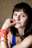 Portrait of a beautiful young brunette with red beads