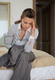 Stressed business woman sitting on bed in hotel room