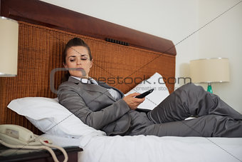 Concerned business woman laying on bed in hotel room and waiting