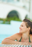 Portrait of happy young woman relaxing in pool and looking on co