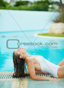 Happy young woman sunbathing at poolside