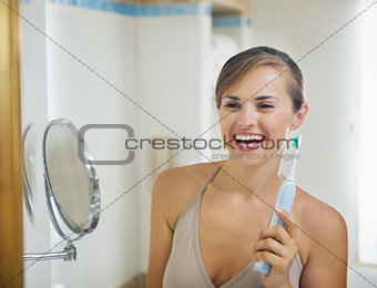 Smiling young woman with electric toothbrush