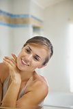 Happy young woman checking facial skin