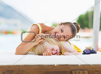 Happy mother and baby playing at poolside