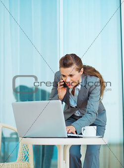 Business woman working with laptop and talking mobile phone on t