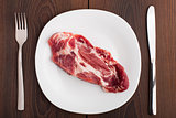 Raw steak on white plate