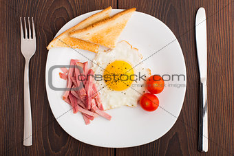 Fried egg with toasts, ham and cherry tomato