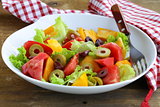 salad of colorful tomatoes and olives on the wooden table