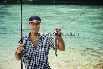 man fishing on river and showing fish to the camera