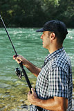 Fisherman standing near river and holding fishing rod