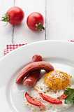 scrambled eggs on a plate with pieces of tomato and sausage