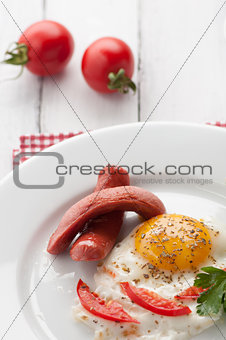 scrambled eggs on a plate with pieces of tomato and sausage