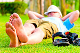 barefoot man is resting on the green grass