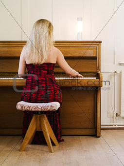 Blond woman playing the piano at home