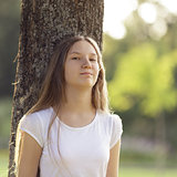 young girl leaning on a tree