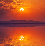 Vibrant rising sun at dawn over water