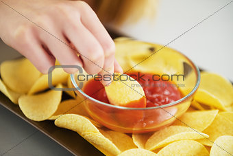 Closeup on girl putting chips in sauce