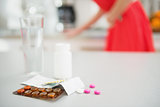 Closeup on pills on table and feeling bad girl in background
