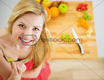 Portrait of smiling young woman making fruits salad