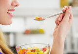 Closeup on happy young woman eating fruits salad