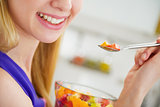 Closeup on smiling young woman eating fruits salad