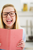 Portrait of happy teenager girl with book in kitchen