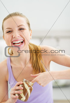 Happy teenager girl eating chocolate cream from jar