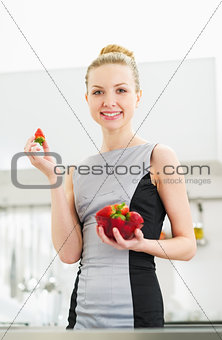 Young housewife eating strawberry in modern kitchen