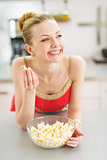 Happy teenager girl eating popcorn in kitchen