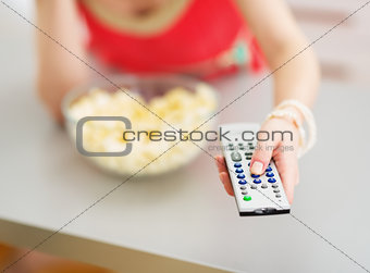 Closeup on tv remote control in hand of young woman