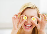 Smiling young woman holding banana slices in front of eyes