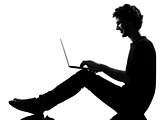 young man silhouette sitting computing laptop