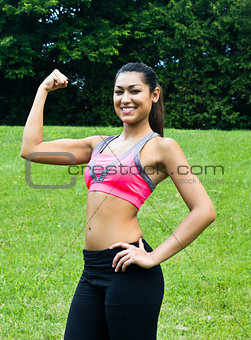 Young fit woman flexes her muscles