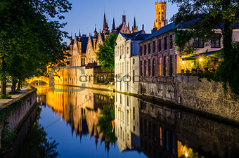 Water canal, medieval houses and bell tower at night in Bruges