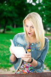 Surprised young woman with book in park