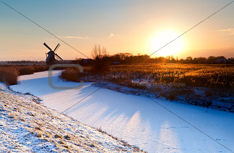 sunrise over Dutch windmill and frozen canal