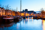 frozen canal with ships in Groningen in dusk
