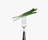 green onion pierced by fork,  isolated on white background 