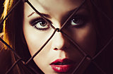 Portrait of beautiful young girl behind the metallic grid. Closeup