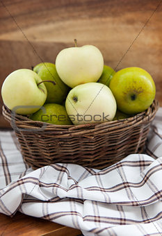 Fresh apples in basket on wooden table 