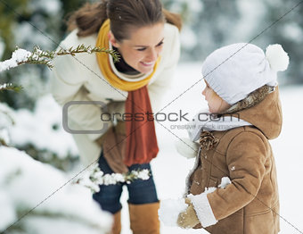Happy mother and baby playing outdoors in winter