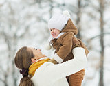 Happy mother playing with baby in winter outdoors
